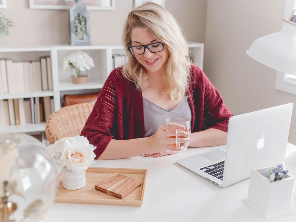Woman smiling with a coffee mug while working on a laptop