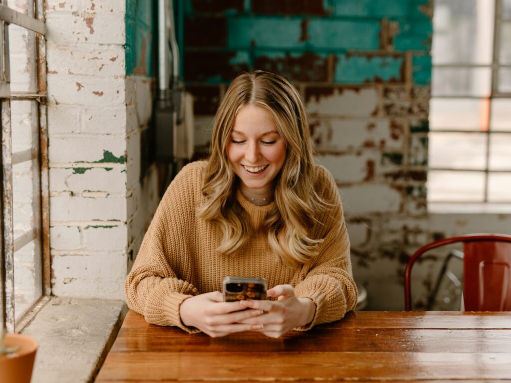 Woman at a cafe table looking up an answer on her phone