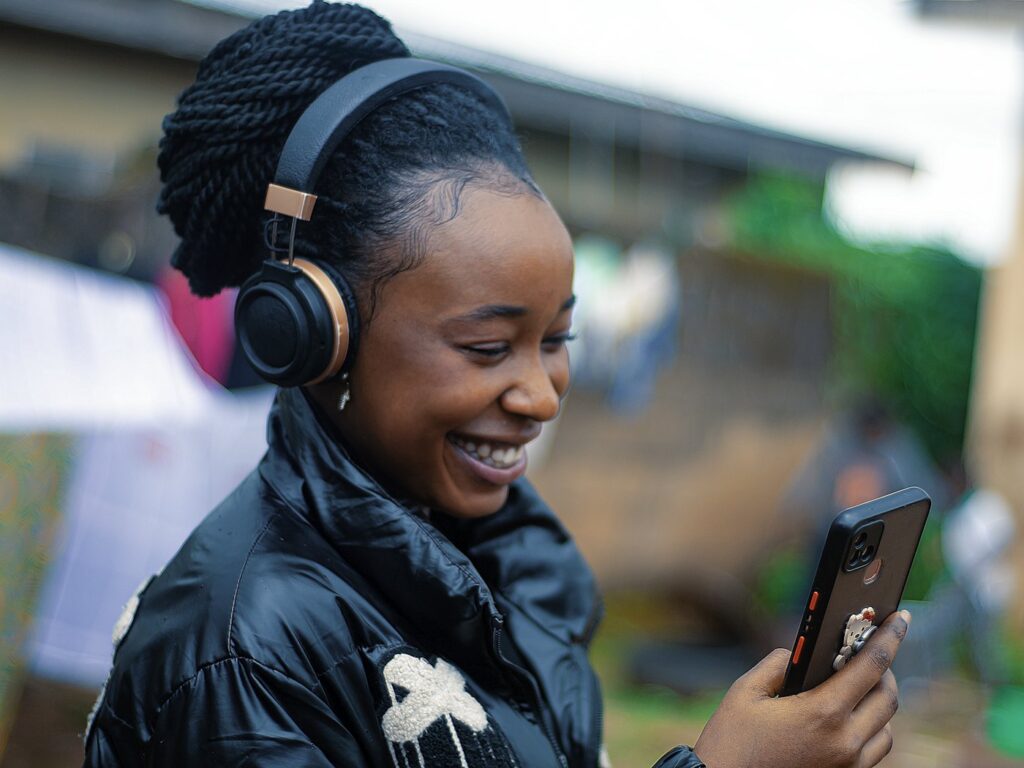 Smiling person with headphones scrolling on their phone