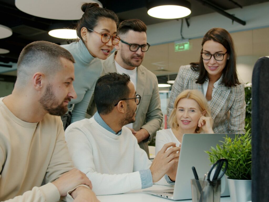 Team collaborating around a laptop in a bright office